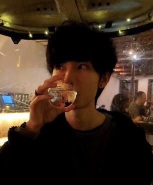 Kennan Ho sipping from a glass in a dimly lit restaurant