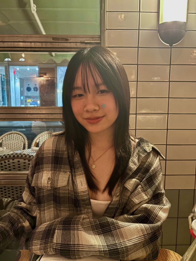 Megan Lin smiling at a café table, in a plaid shirt