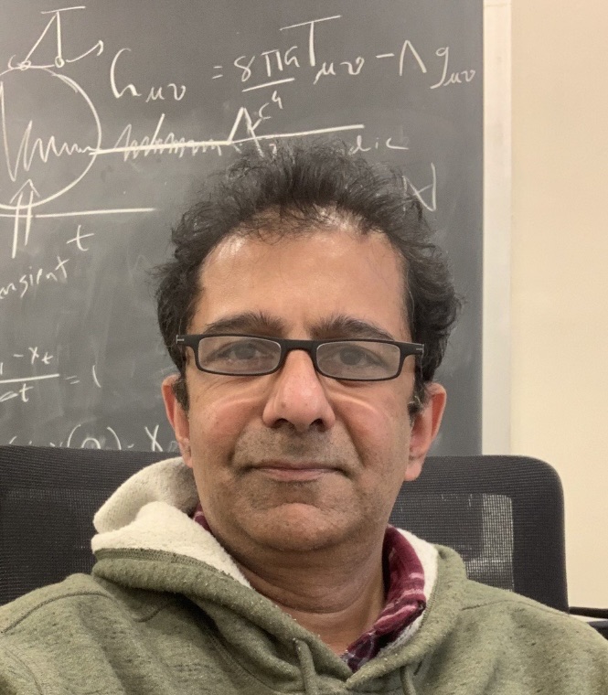 Trush Majmudar in front of a chalkboard covered in equations